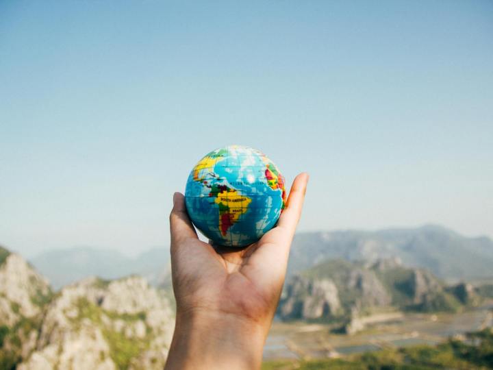person holding world globe facing mountain