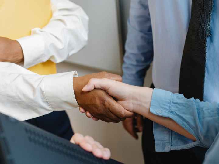 multiracial colleagues shaking hands at work
